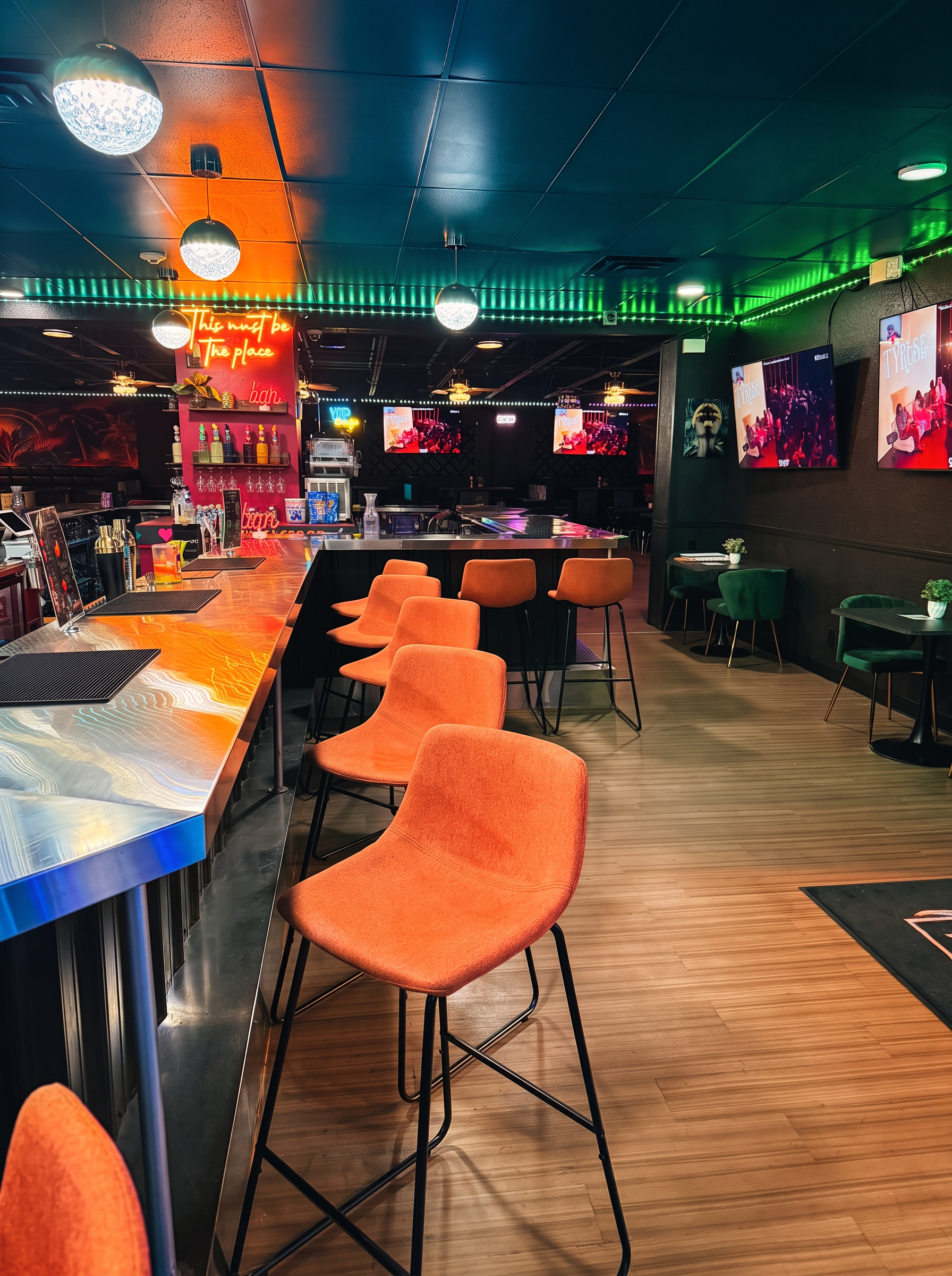 Wide view of the Olivia 91 bar and lounge with green velvet seating and neon signage